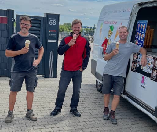 Drei Mitarbeiter mit einem Eis in der Hand vor einem Eiswagen